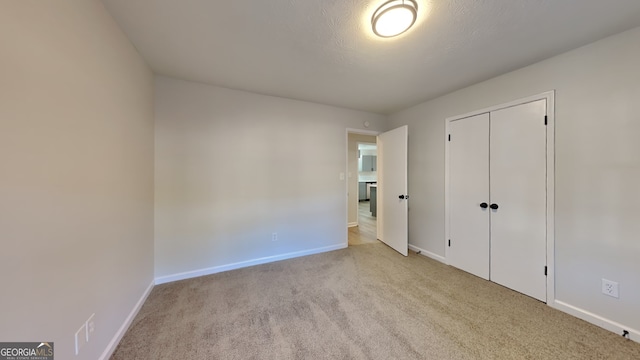 unfurnished bedroom featuring a textured ceiling, a closet, carpet flooring, and baseboards