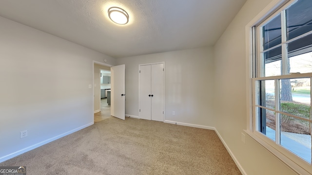 unfurnished bedroom with a textured ceiling, a closet, carpet, and baseboards