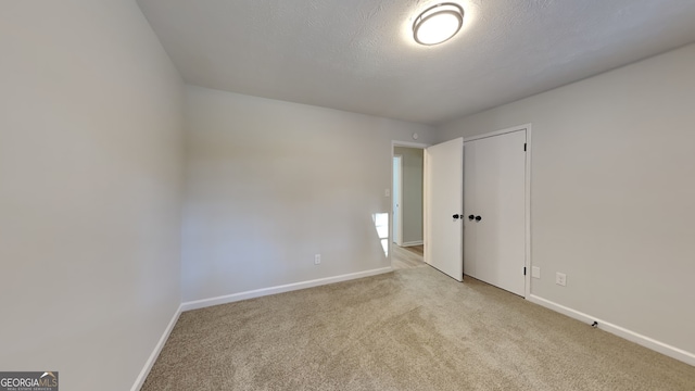 unfurnished bedroom with carpet floors, a closet, baseboards, and a textured ceiling