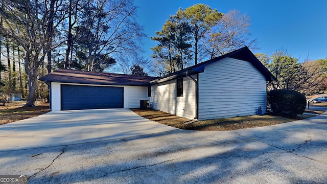 view of property exterior with concrete driveway, central AC unit, and an attached garage