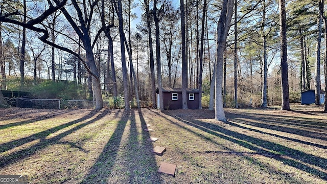 view of yard featuring an outbuilding, driveway, a storage shed, and fence