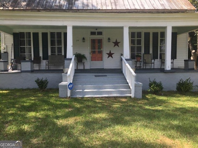 view of exterior entry featuring covered porch and a yard