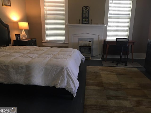 bedroom with heating unit and a fireplace