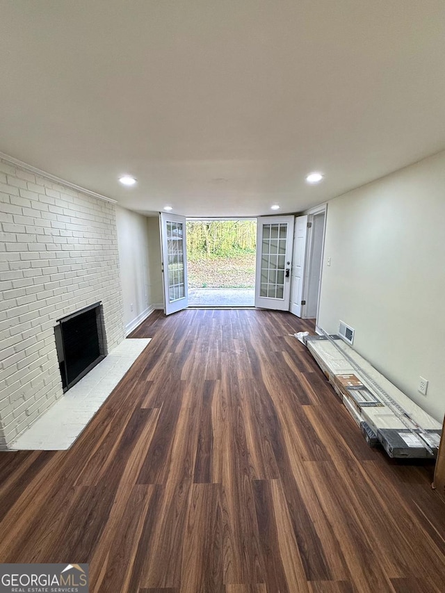 unfurnished living room featuring dark wood-style floors, floor to ceiling windows, recessed lighting, visible vents, and a brick fireplace