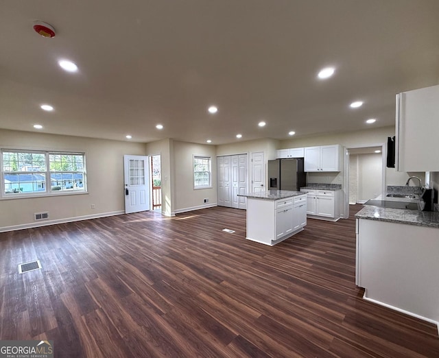 kitchen featuring open floor plan, visible vents, stainless steel refrigerator with ice dispenser, and a center island