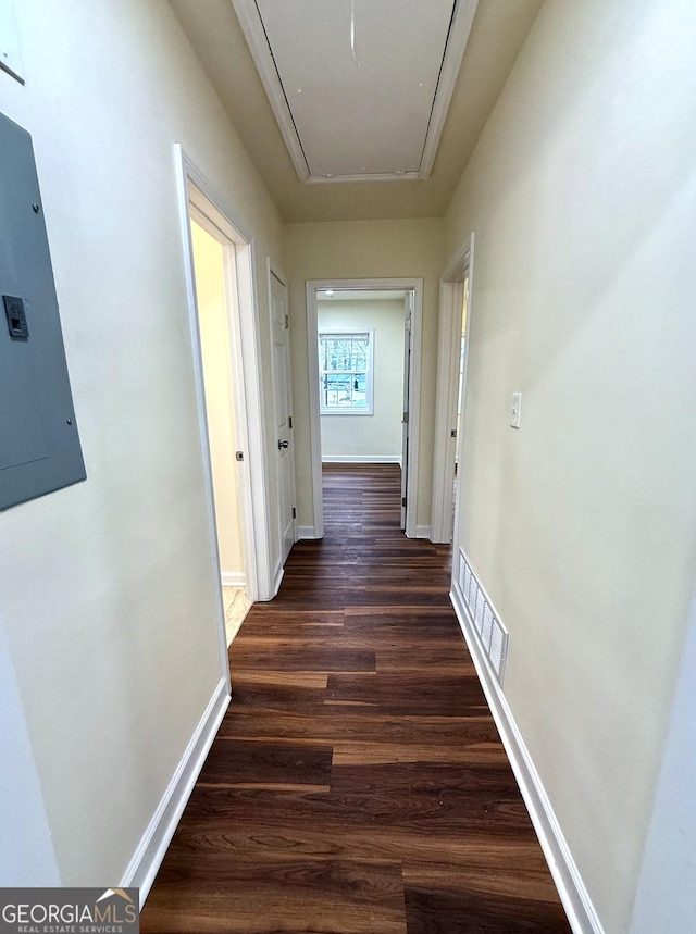 hallway featuring wood finished floors, visible vents, baseboards, electric panel, and attic access