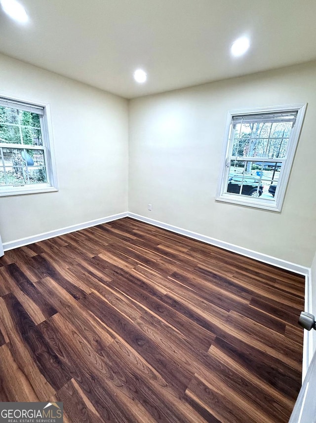 empty room with dark wood-style floors, recessed lighting, a healthy amount of sunlight, and baseboards