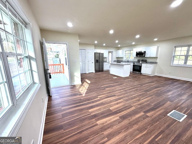 unfurnished living room featuring dark wood-type flooring, recessed lighting, visible vents, and baseboards