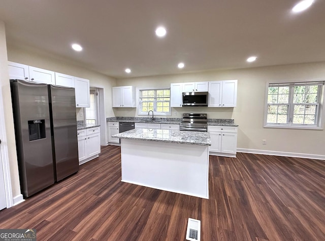 kitchen with appliances with stainless steel finishes, a sink, visible vents, and white cabinetry