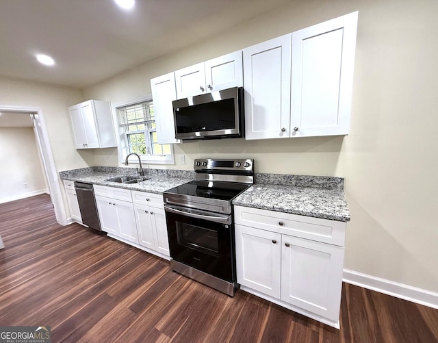 kitchen featuring stainless steel appliances, dark wood-type flooring, a sink, and white cabinetry