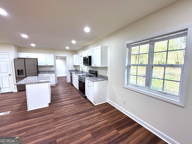 kitchen with dark wood-type flooring, a sink, baseboards, appliances with stainless steel finishes, and light stone countertops