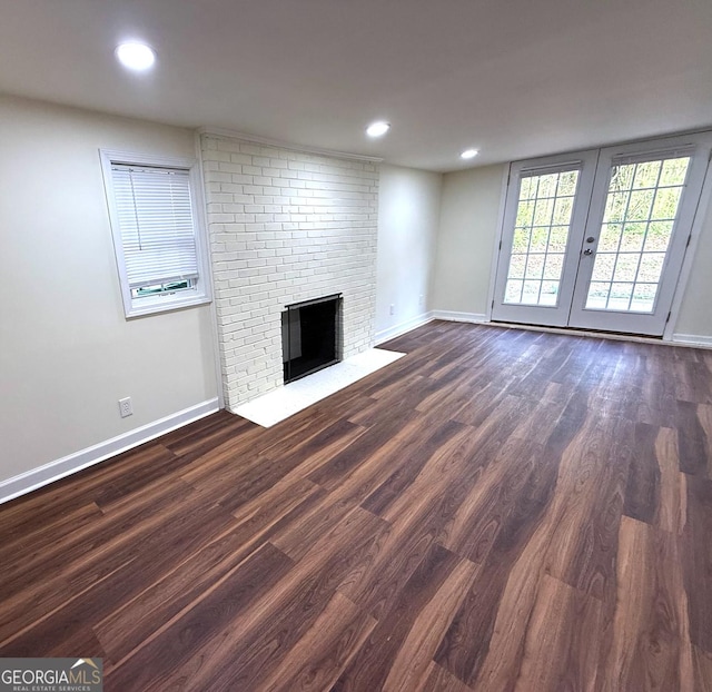 unfurnished living room with a brick fireplace, baseboards, dark wood-type flooring, and recessed lighting