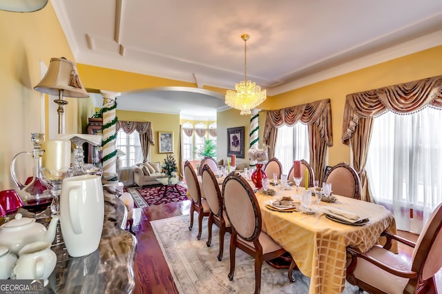 dining area featuring crown molding, arched walkways, wood finished floors, and a notable chandelier