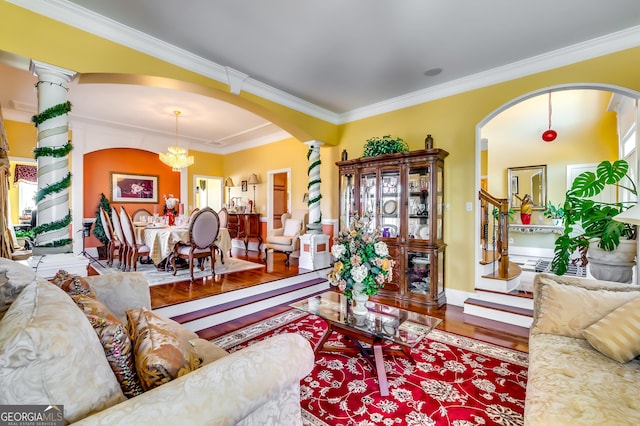 living area with arched walkways, crown molding, and wood finished floors