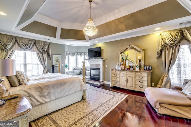 bedroom featuring a glass covered fireplace, ornamental molding, dark wood finished floors, and visible vents