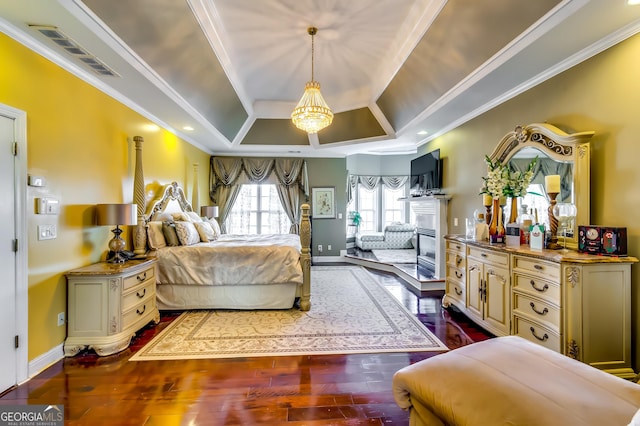 bedroom with baseboards, visible vents, a raised ceiling, dark wood-style floors, and ornamental molding