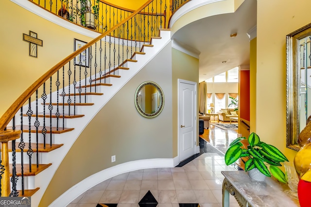 stairway featuring a towering ceiling, baseboards, and tile patterned floors