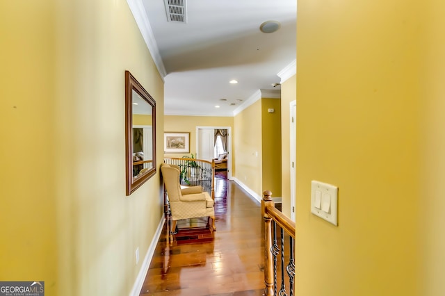 corridor with baseboards, visible vents, crown molding, and hardwood / wood-style floors