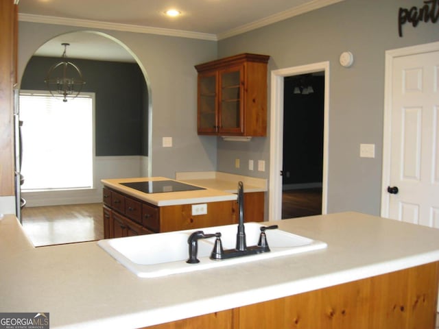 kitchen featuring a chandelier, glass insert cabinets, black electric cooktop, and brown cabinets