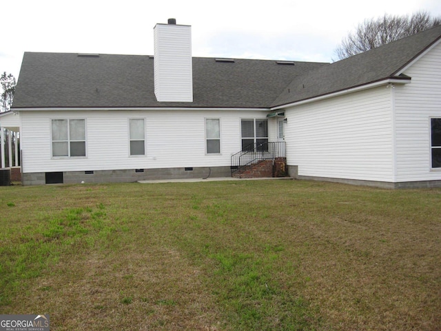 back of house with roof with shingles, crawl space, a chimney, and a lawn