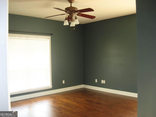 spare room featuring baseboards, dark wood finished floors, and a ceiling fan