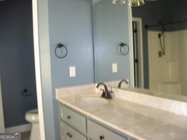 bathroom with toilet, a shower, and vanity