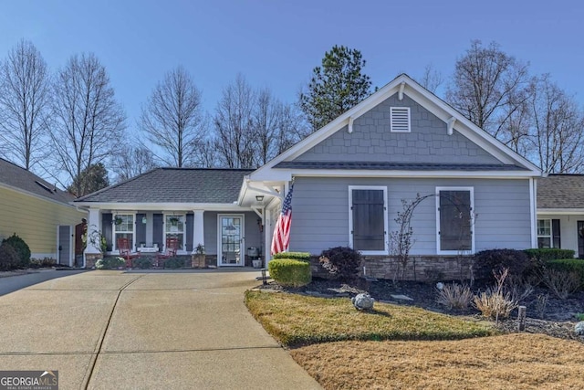 view of front of house with stone siding, roof with shingles, and driveway