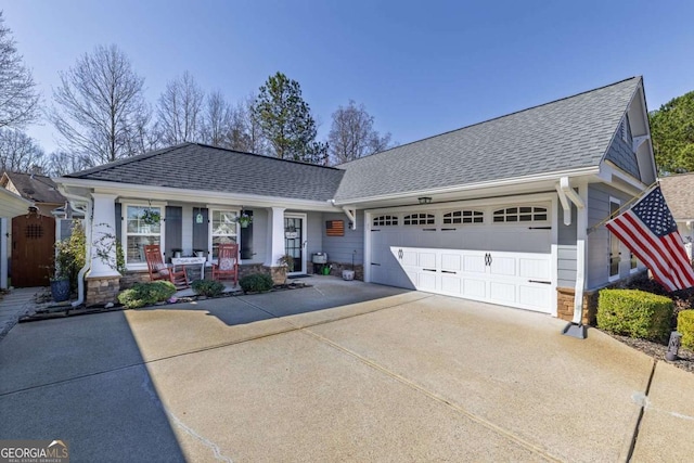 view of front of house featuring driveway, covered porch, a shingled roof, and a garage