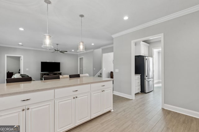 kitchen featuring light wood-style flooring, white cabinets, baseboards, freestanding refrigerator, and pendant lighting