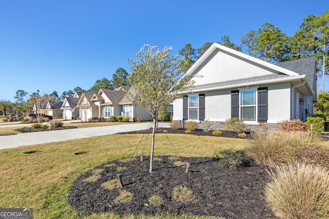 view of front of house with metal roof, concrete driveway, stucco siding, a front lawn, and a standing seam roof