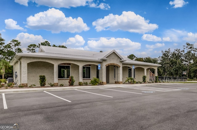 view of building exterior with uncovered parking and fence