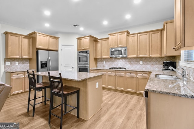 kitchen with light stone counters, stainless steel appliances, a kitchen island, a sink, and visible vents