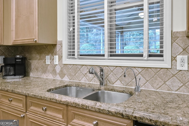 kitchen featuring tasteful backsplash, a sink, and light stone countertops