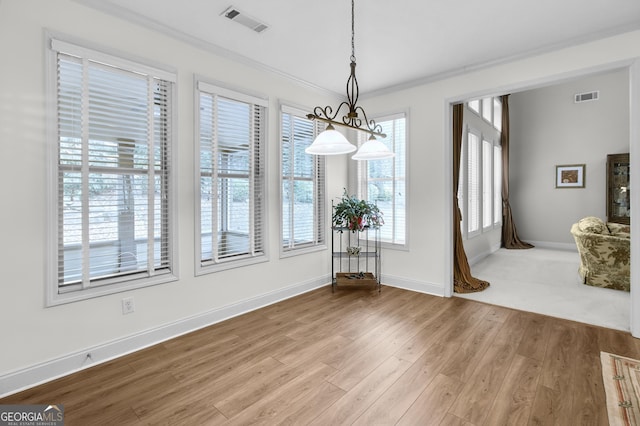 unfurnished dining area with baseboards, wood finished floors, visible vents, and crown molding