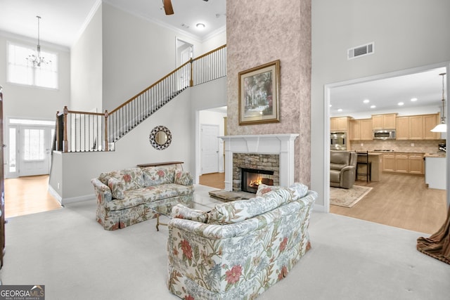 living area featuring a stone fireplace, ornamental molding, a towering ceiling, and visible vents