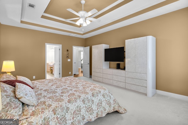 carpeted bedroom with visible vents, baseboards, ornamental molding, a tray ceiling, and ensuite bath