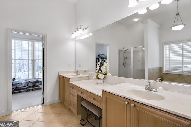 bathroom with double vanity, a shower stall, a sink, and tile patterned floors