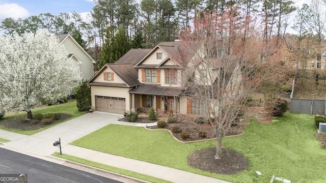 craftsman inspired home with a shingled roof, concrete driveway, an attached garage, and a front lawn