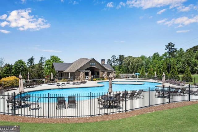 community pool with a patio area and fence