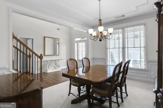 dining room featuring ornamental molding, wainscoting, visible vents, and a decorative wall