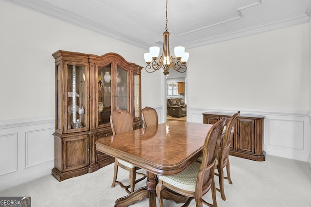 dining area featuring light carpet, wainscoting, a chandelier, and ornamental molding