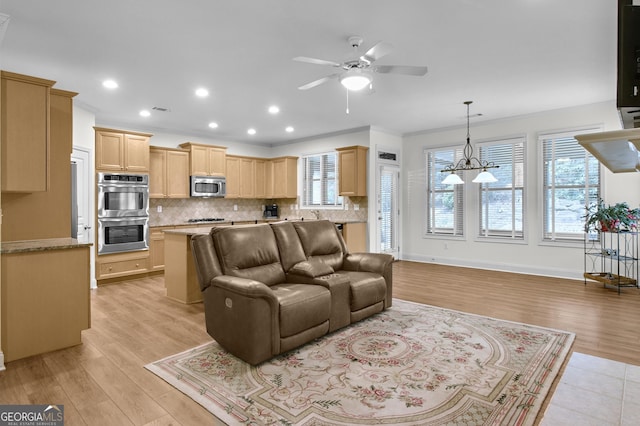 living room featuring ornamental molding, light wood finished floors, a ceiling fan, and baseboards