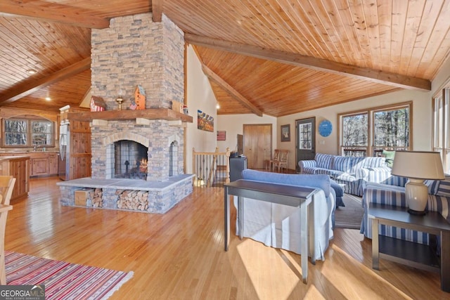 living room with beamed ceiling, light wood-type flooring, a fireplace, and wood ceiling