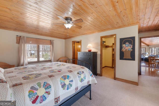 bedroom featuring baseboards, light colored carpet, wooden ceiling, ornamental molding, and a spacious closet