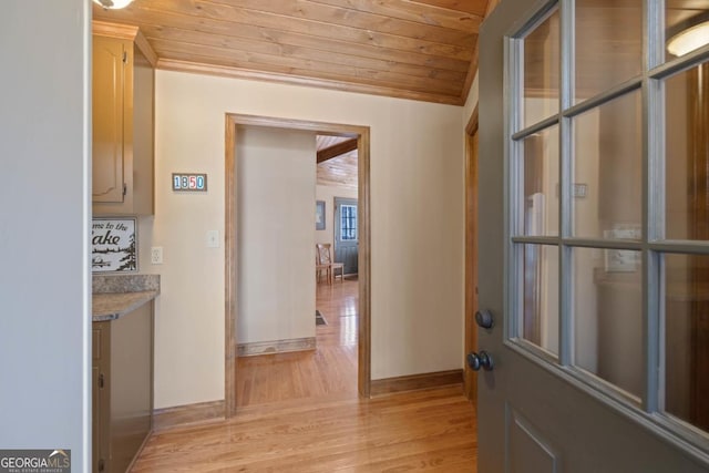 foyer with wood ceiling, baseboards, light wood-style flooring, and crown molding