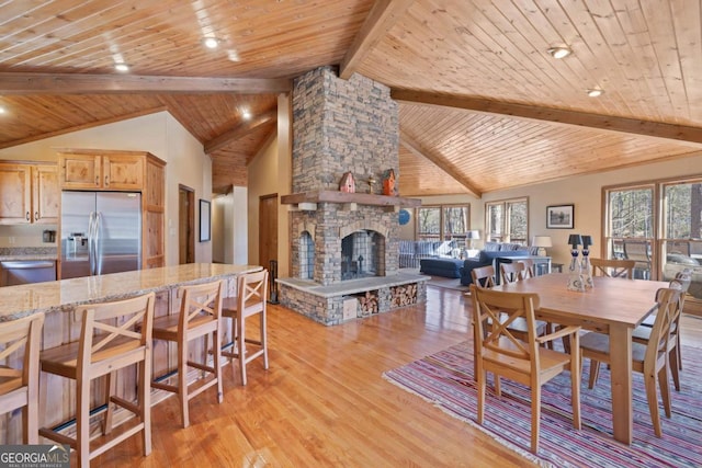 dining space featuring wooden ceiling, a healthy amount of sunlight, a fireplace, and light wood finished floors