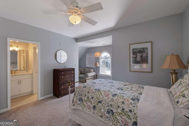 bedroom featuring light carpet, baseboards, ceiling fan, ensuite bathroom, and a sink