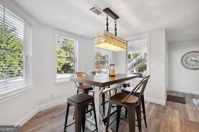 dining space featuring a healthy amount of sunlight, light wood-style flooring, visible vents, and baseboards