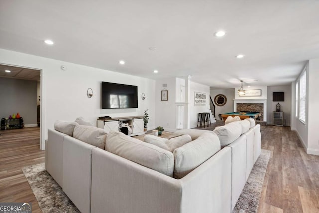 living room featuring light wood-style floors, recessed lighting, a fireplace, and baseboards