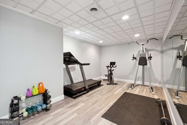 exercise area with a paneled ceiling, visible vents, baseboards, and wood finished floors